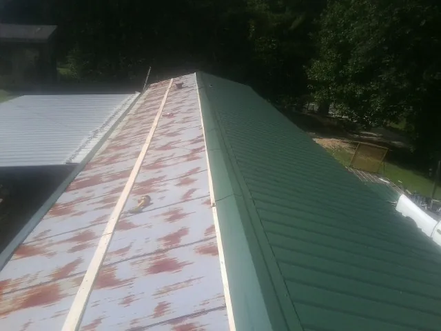 Old rusted panels beside newly installed green metal roofing — Wind Damage Roof Repair by Roofing Brothers in Okarche