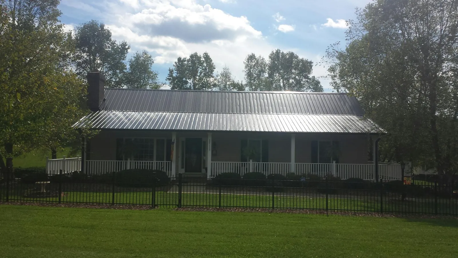 Gray metal roof on a brick ranch with a full width front porch — Gutter Guard Installation work by our crew in Okarche