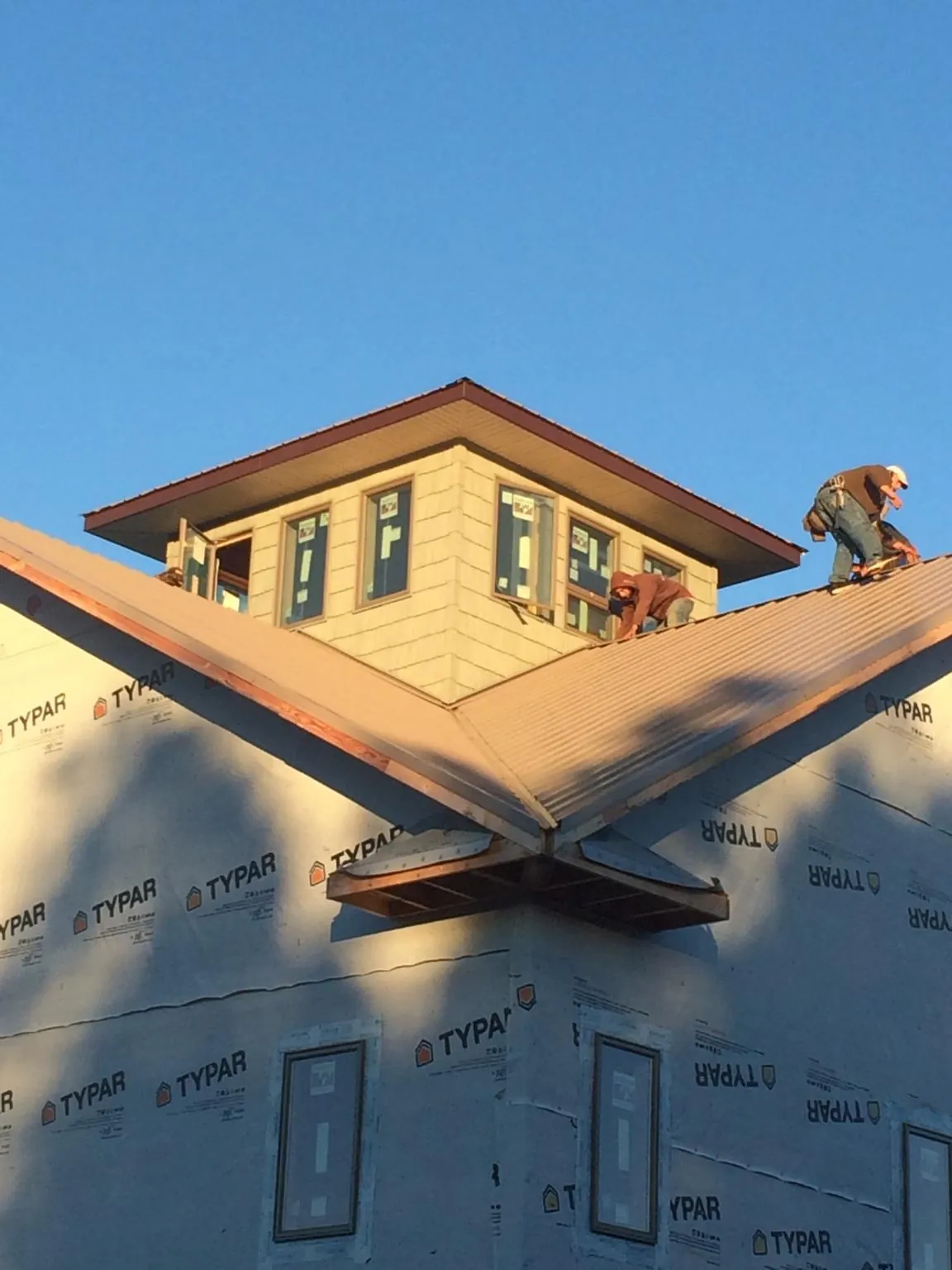 Roofers working around a rooftop cupola on a new metal roof at sunset — Roof Waterproofing in Okarche by Roofing Brothers